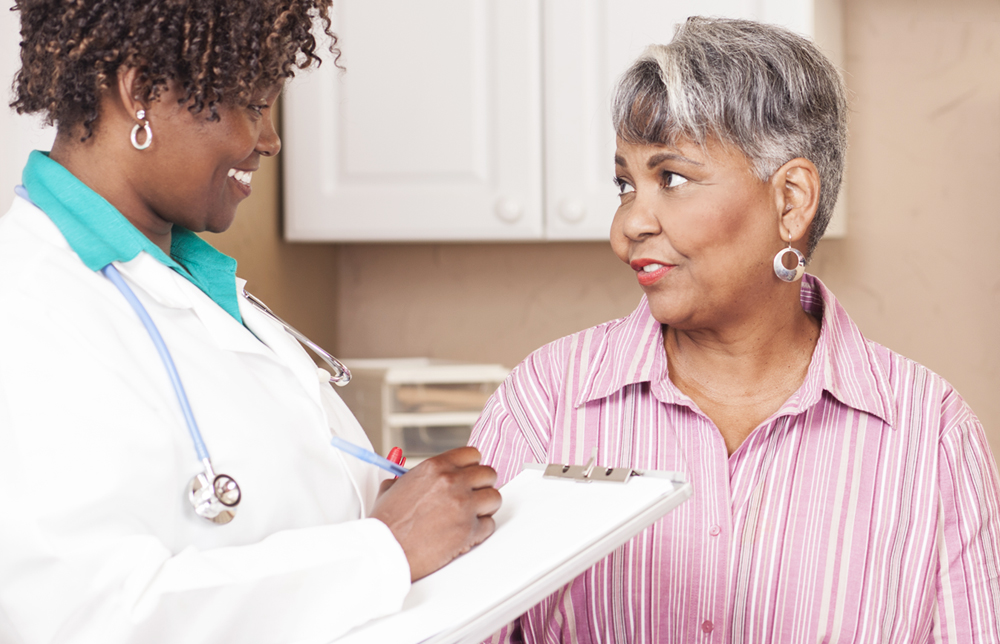 Photo of a doctor and a senior female patient having a discussion in an exam room